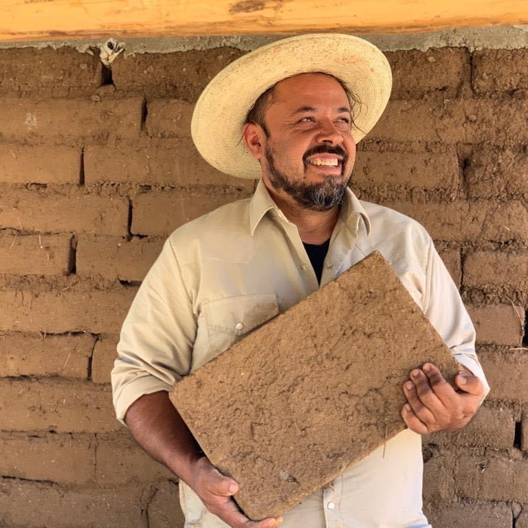 Artist Sandro Canovas holds a home-made adobe brick